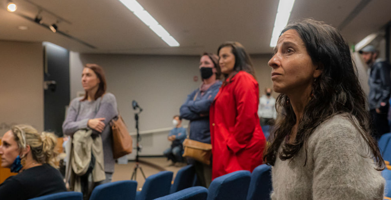 Side image of parents, attendees of indoor school board meeting