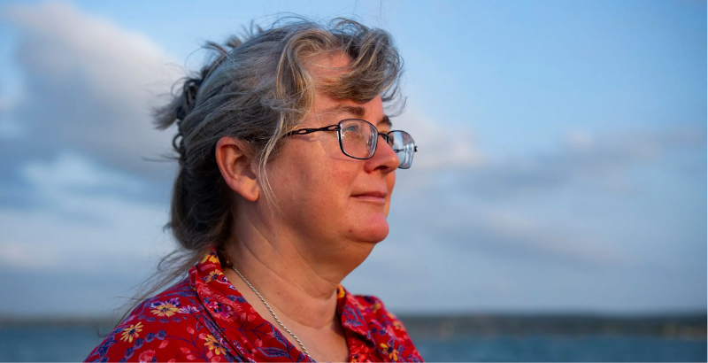 Portrait image of woman (librarian) from side, in front of body of water