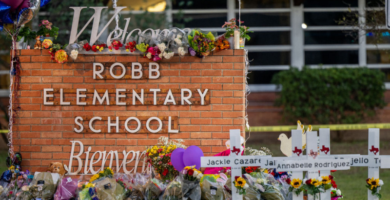 Image of Robb Elementary sign covered in flowers, crosses with children' names