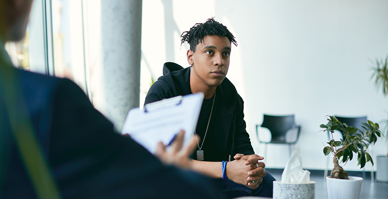 A stock photo of a teenage boy having counselling with mental health professional during therapy session