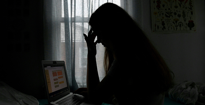 Silhouette of a student looking at a computer in a dim room