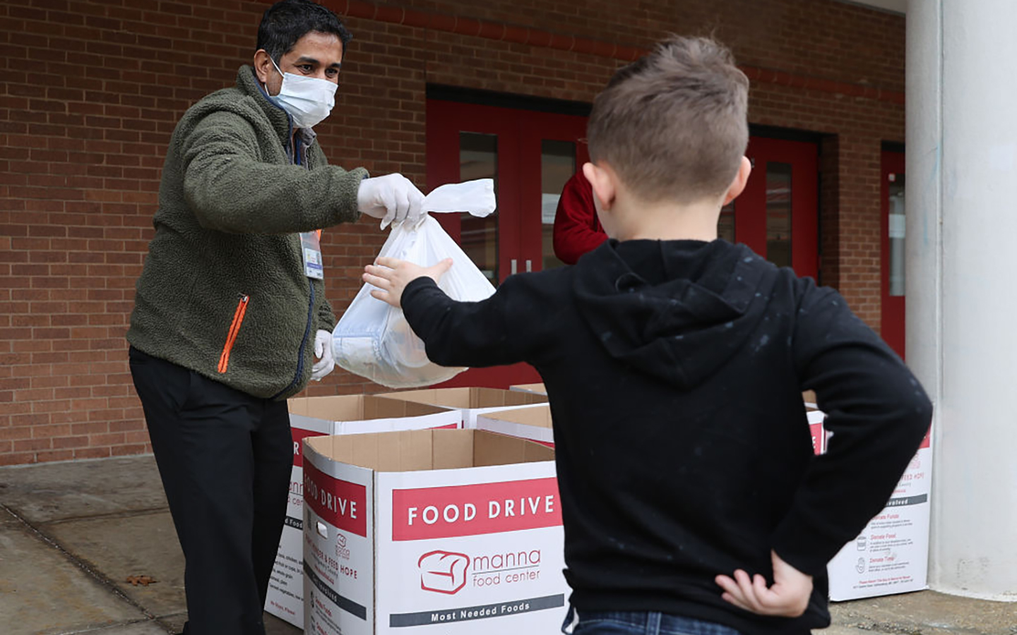 A young child collects a bag of food at a food drive