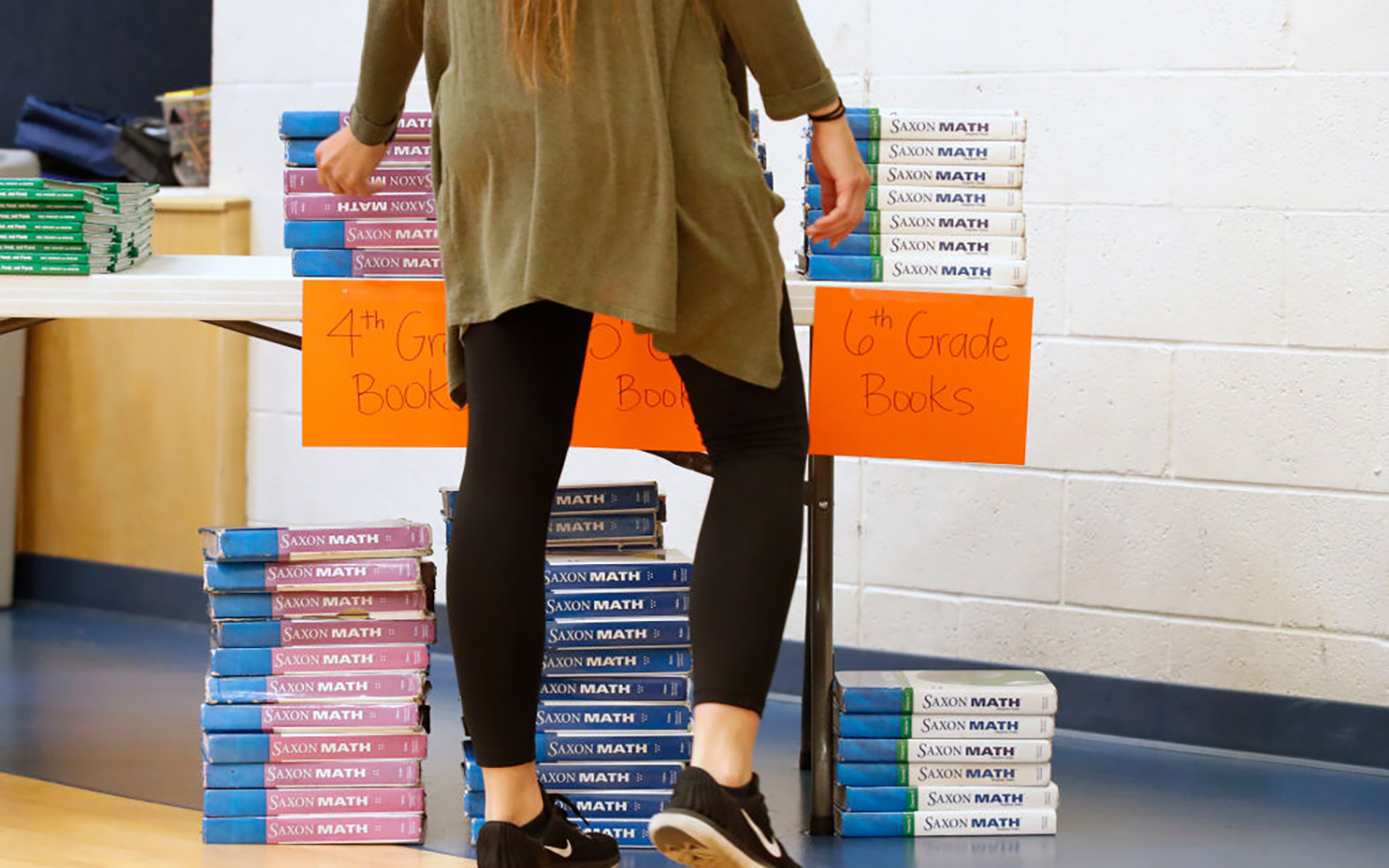 A photo of a teacher standing in front of piles of math textbooks