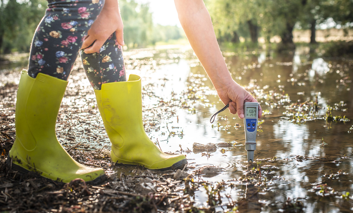 student testing water in river