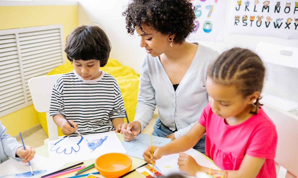 a stock photo of a teacher painting with young students