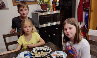 Three kids gathered around a kitchen table