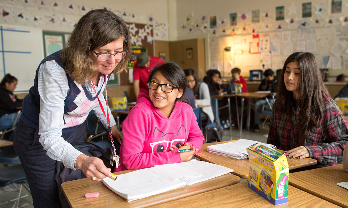 A teacher works with a student in a middle-school classroom