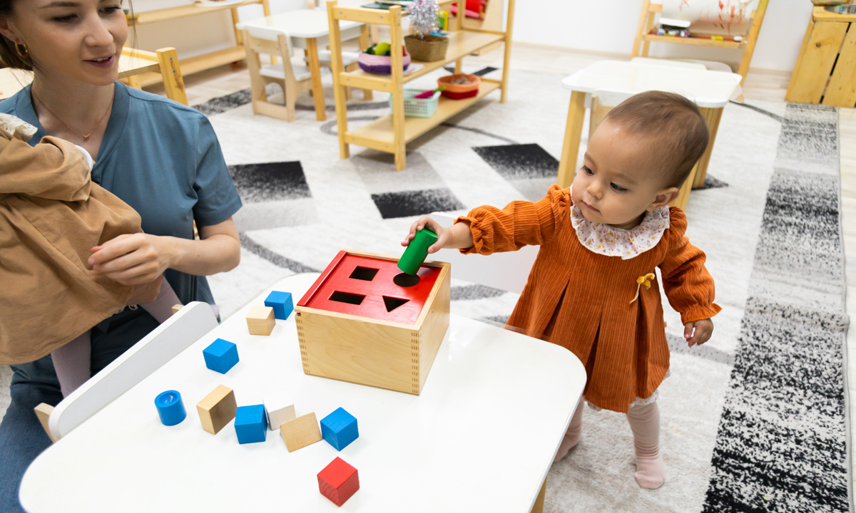 A toddler playing with blocks with caregiver
