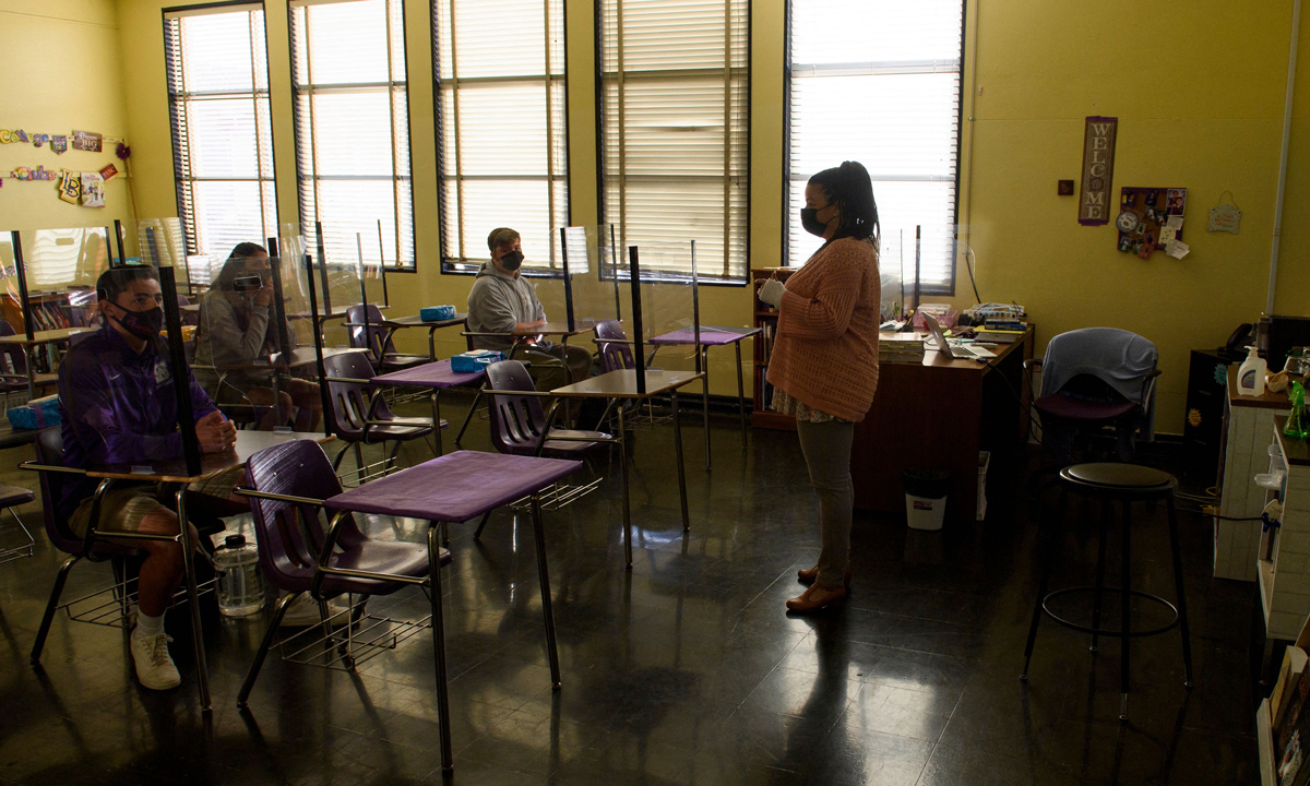 A photo of a classroom during COVID with just a few students and many empty desks