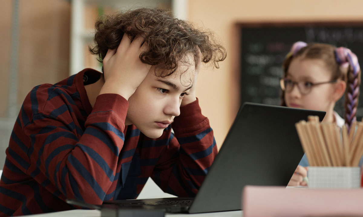 This photo shows a student struggling with schoolwork on a laptop.