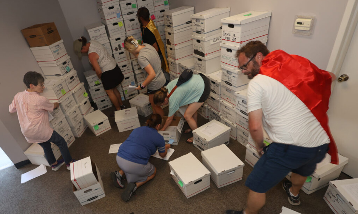 A photo of cape-wearing volunteers for Citizens for Arkansas Public Education and Students (CAPES) at a secretary of state facility delivering boxes of petitions