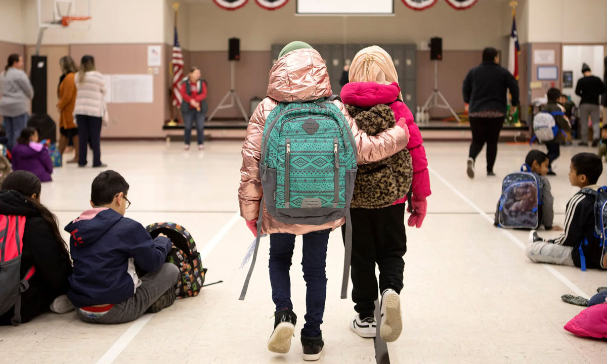 This is a photo of two students walking side-by-side down a school hallway