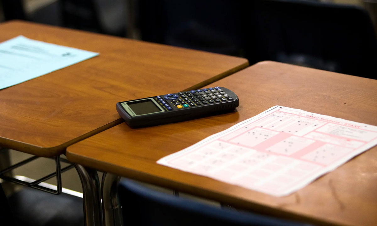 This is a photo of a calculator and a test scantron on a desk.