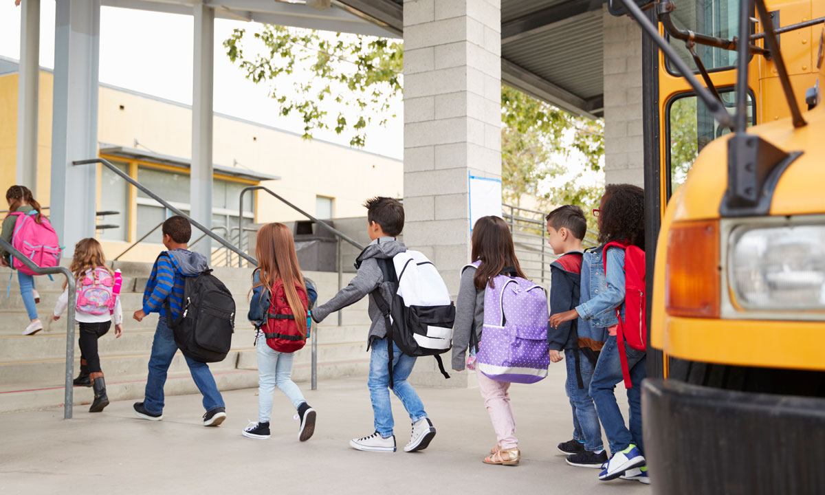 This photo shows young children getting off a school bus.