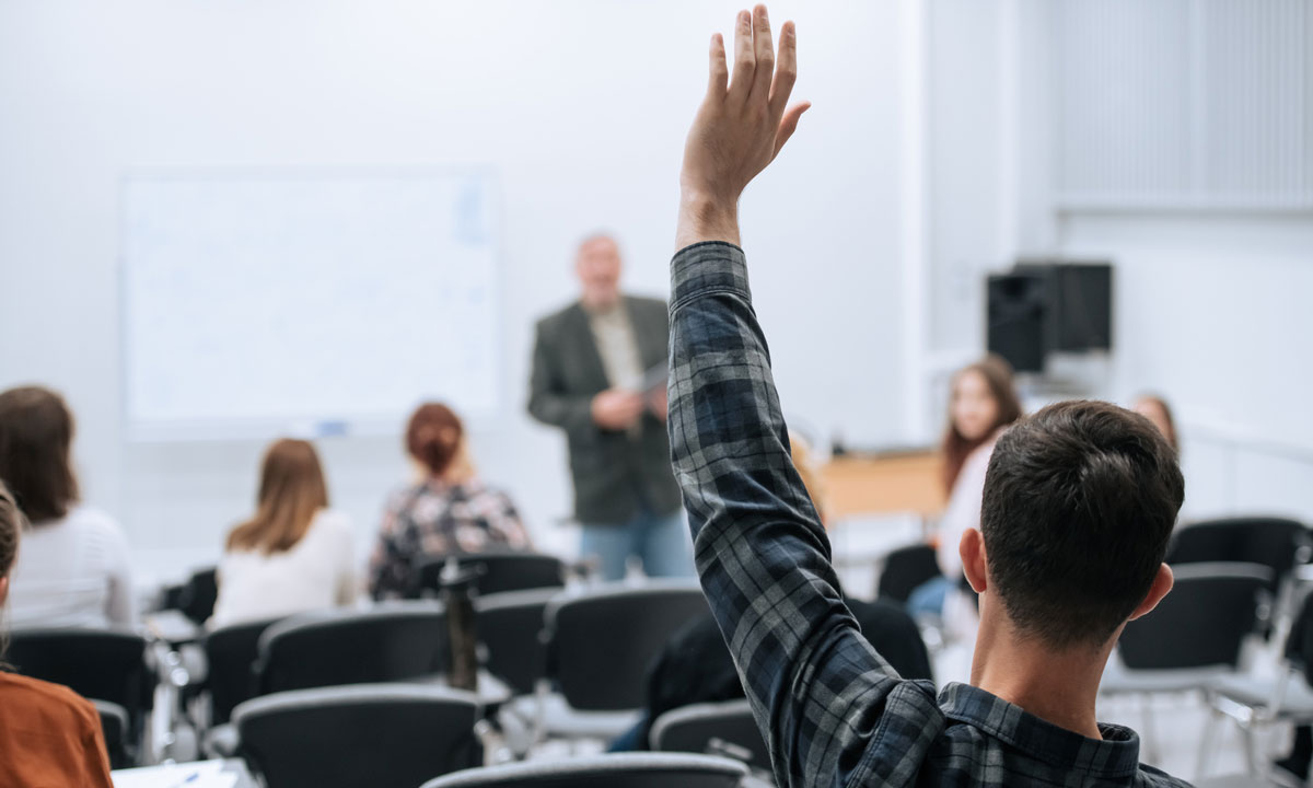 This photo shows a student raising his hand in class.
