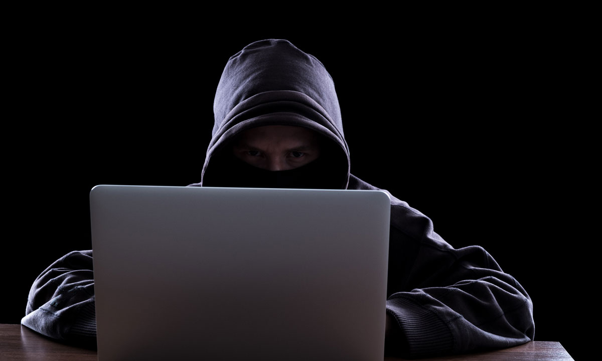 This is a photo of a man in a hoodie on a laptop.
