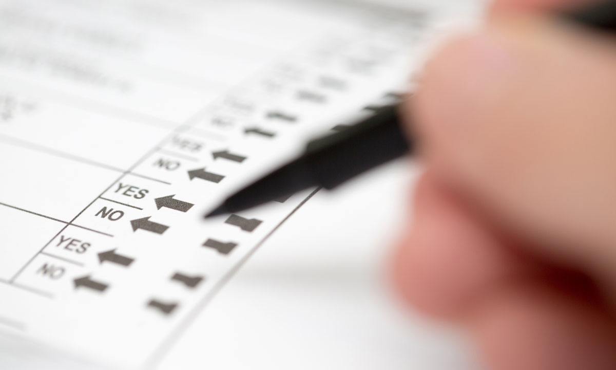 This is a photo of someone writing on a voting ballot.