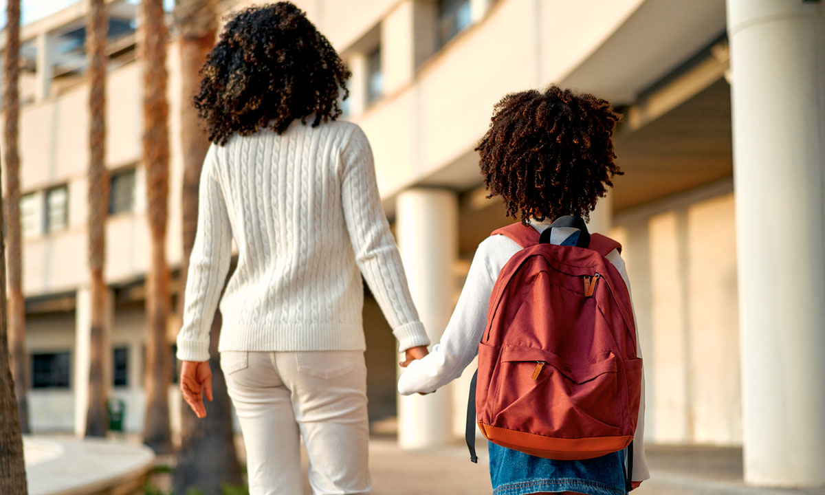 This is a photo of a mom and young girl with a backpack walking