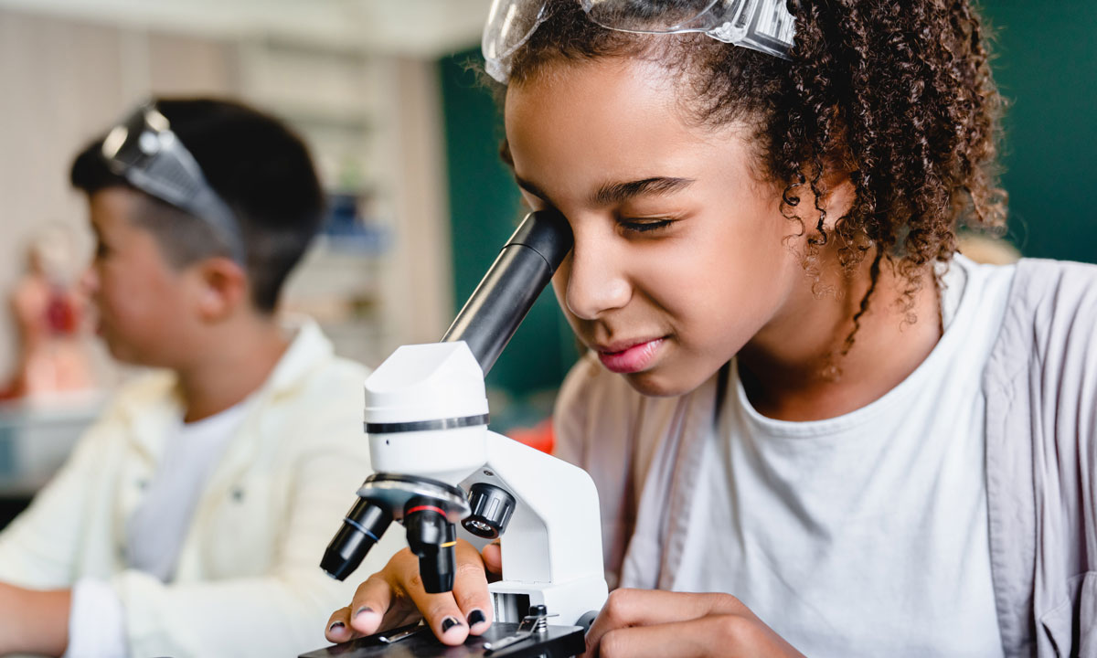 This is a photo of a female student looking into a microscope in class.