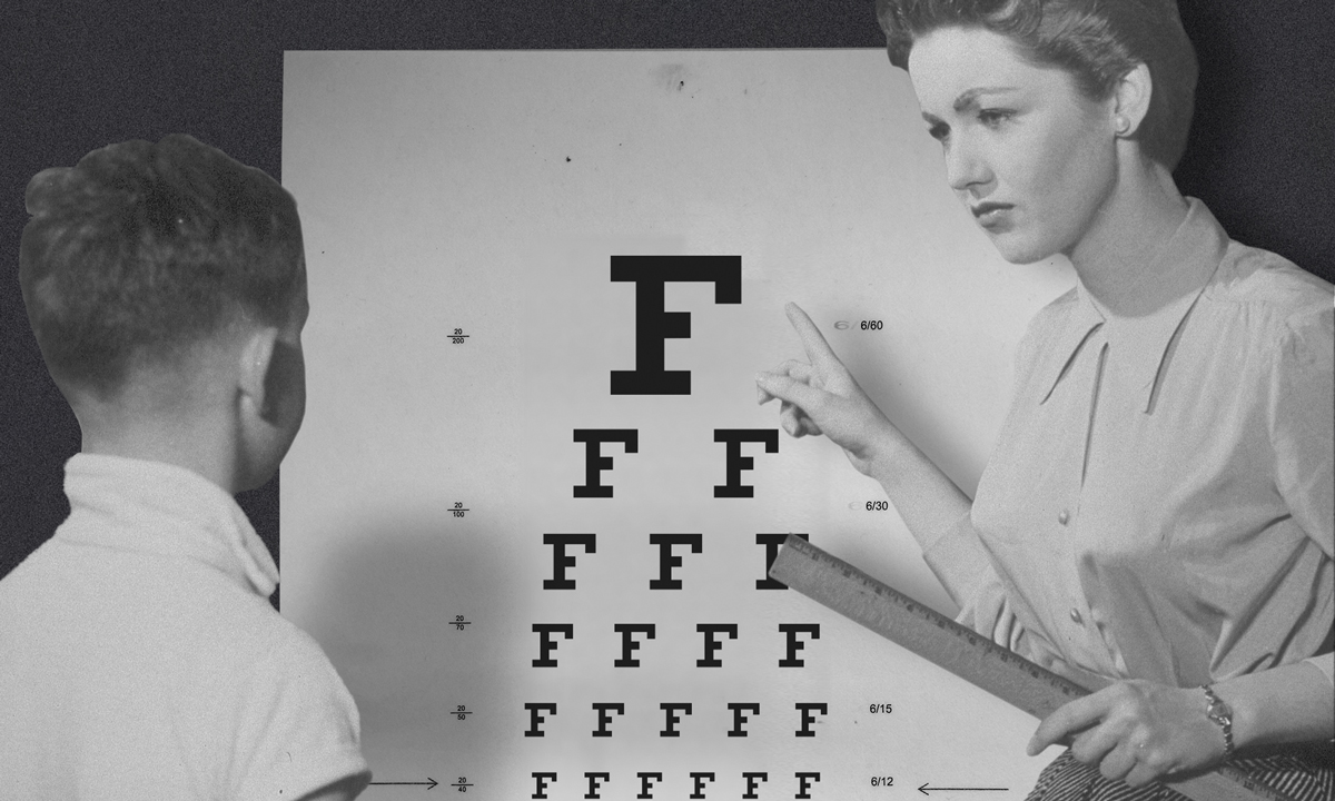 This is a black and white photo of a child reading an eye exam chart.