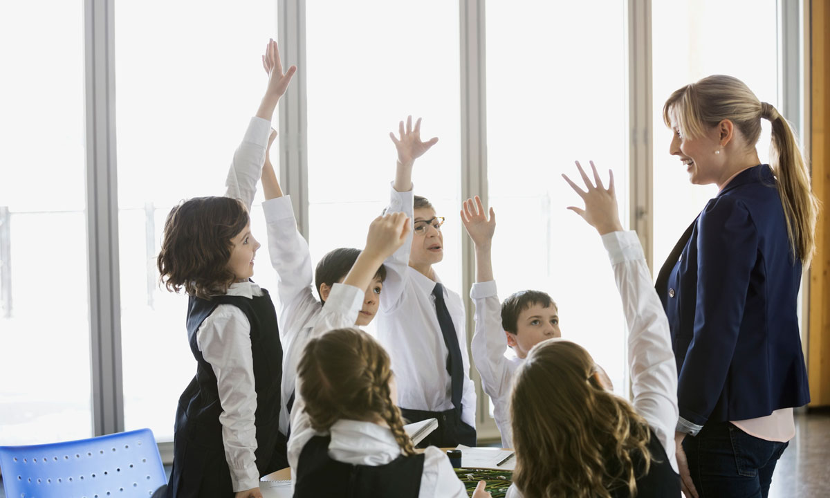 This is a photo of students raising their hands to their teacher.