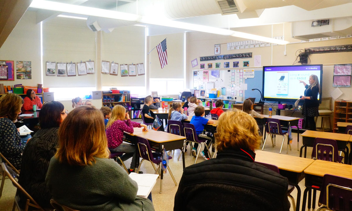 This is a photo of teachers in a classroom evaluating a reading lesson.