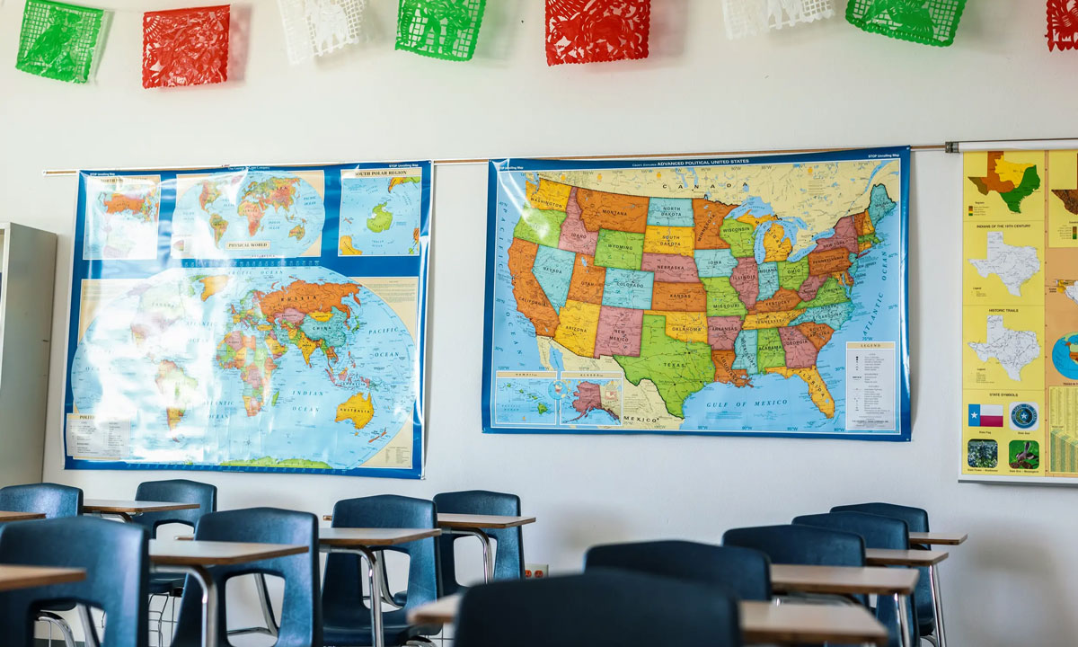 This is a photo of an empty classroom with a United States map and world map on the wall.