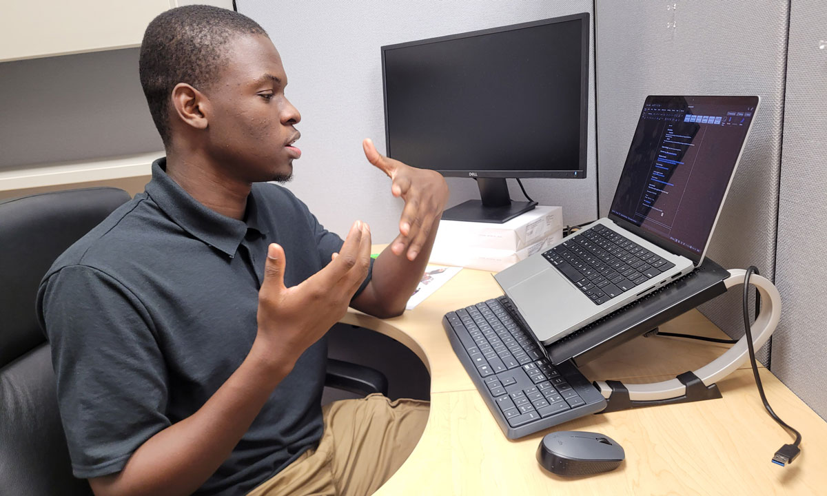 This is a photo of a student sitting at a desk with a laptop.