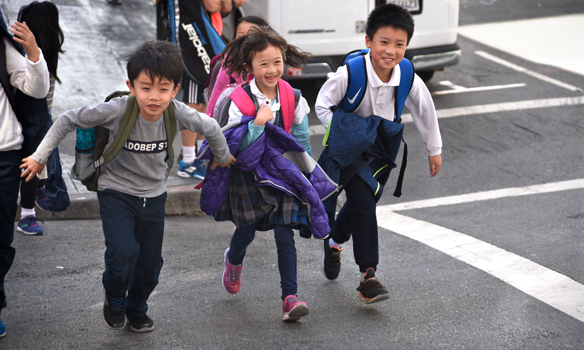 This is a photo of three young Asian American students walking with backpacks.