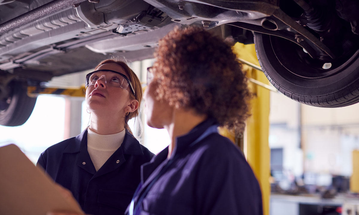 This is a photo of a student in vocational school being trained on car mechanics by her instructor.