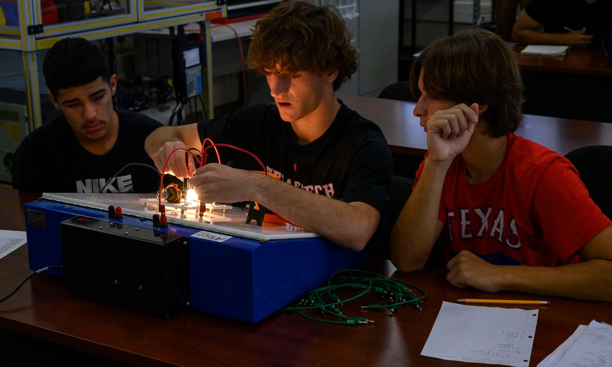 This is a photo of three students working on an electrical circuit.