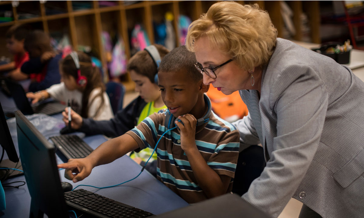 This is a photo of Carey Wright helping a student on the computer.