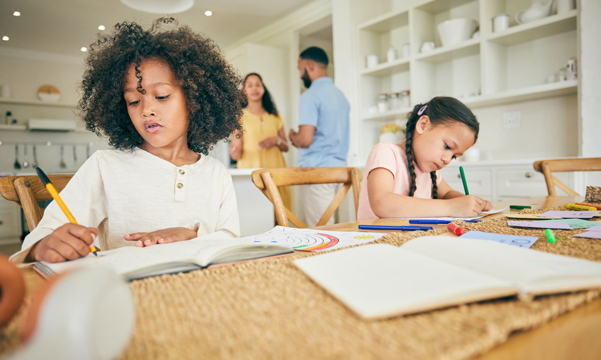 This is a photo of two homeschooled girls doing their work at the kitchen table.