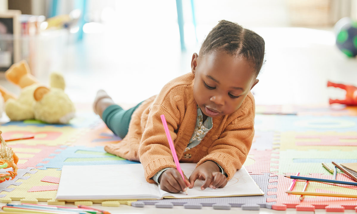 This is a photo of a little girl writing while laying on the floor.