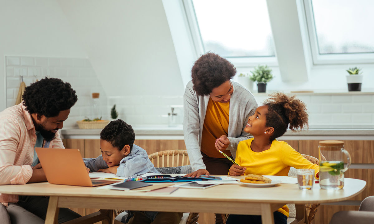 This is photo of an African American mom and dad homeschooling their son and daughter.