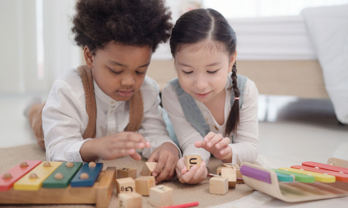 This is a photo of two young girls playing with blocks and xylophones.