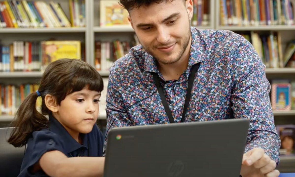 This is a photo of Nick Dinelaris, a Chapter One “early literacy interventionist,” helping a student on a laptop.