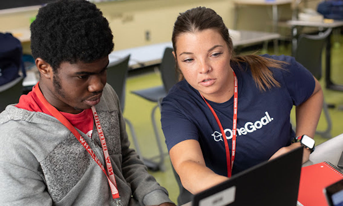 This is a photo of a OneGoal worker helping a student apply for financial aid.