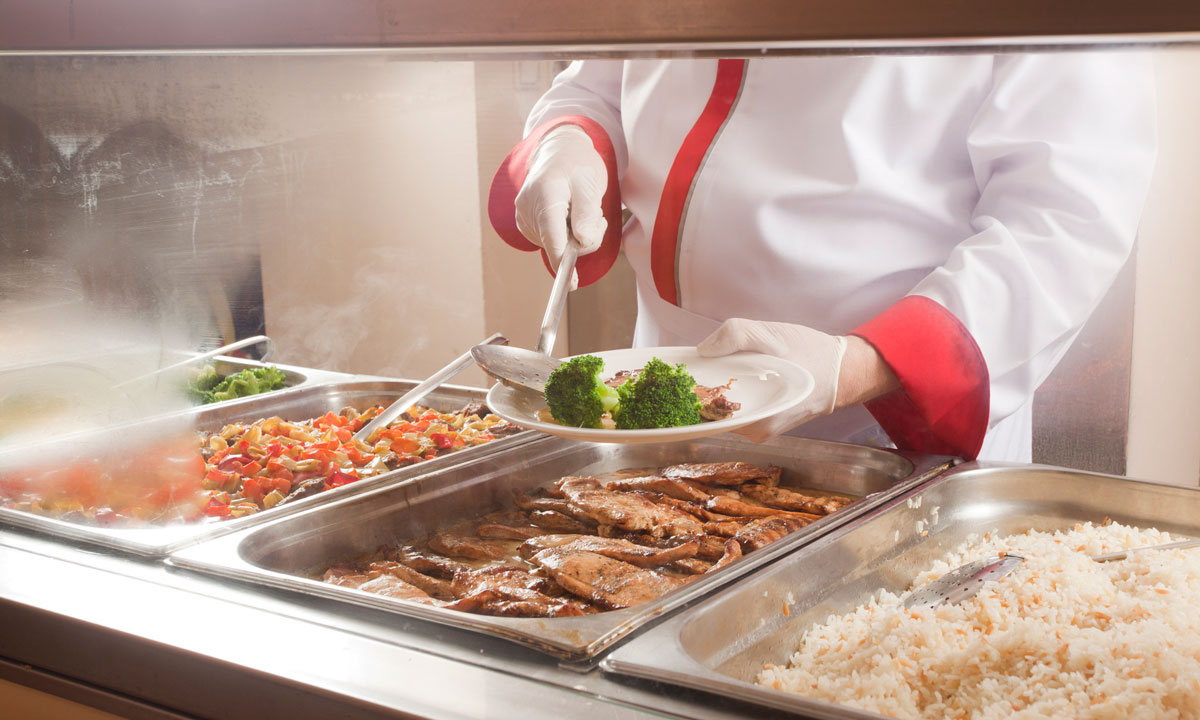 This is a photo of a school cafeteria worker serving food.