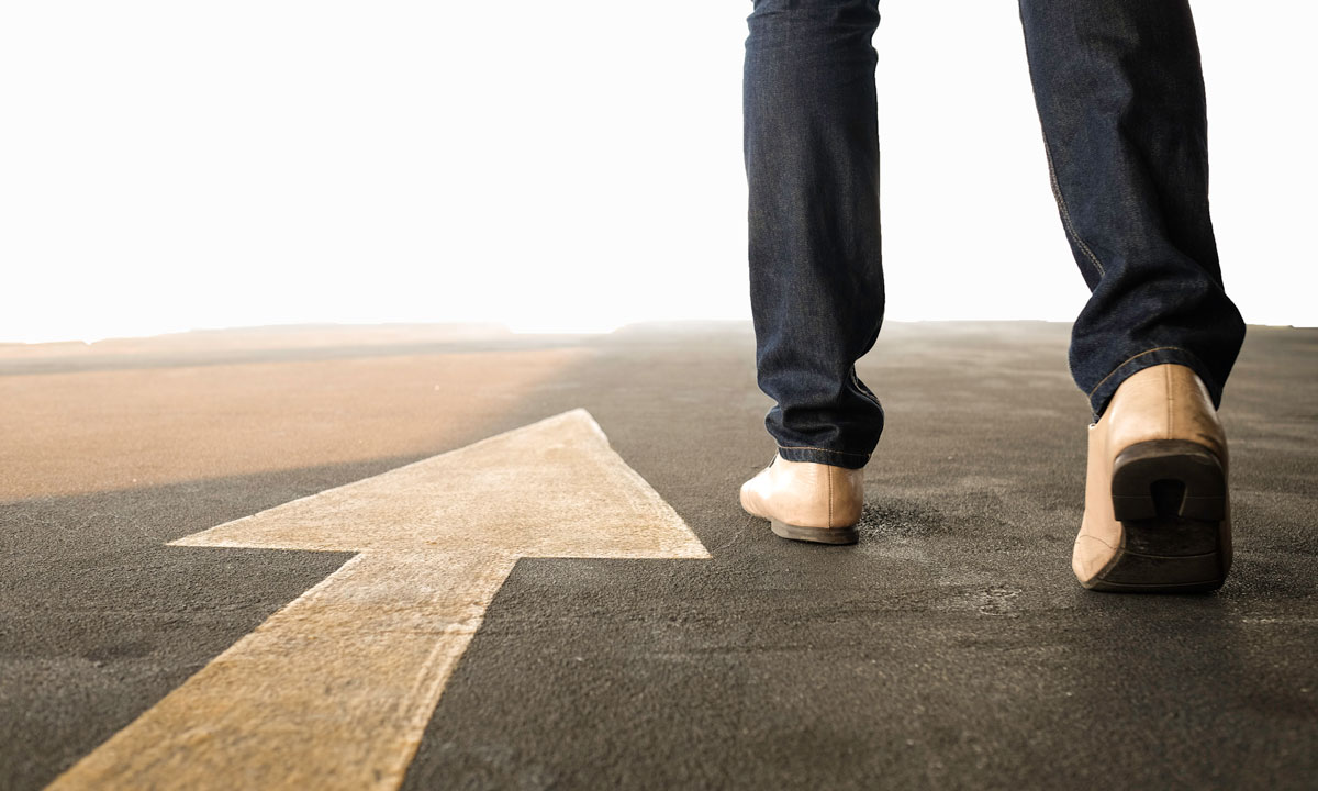 This is a photo of a person walking on a road with an arrow.