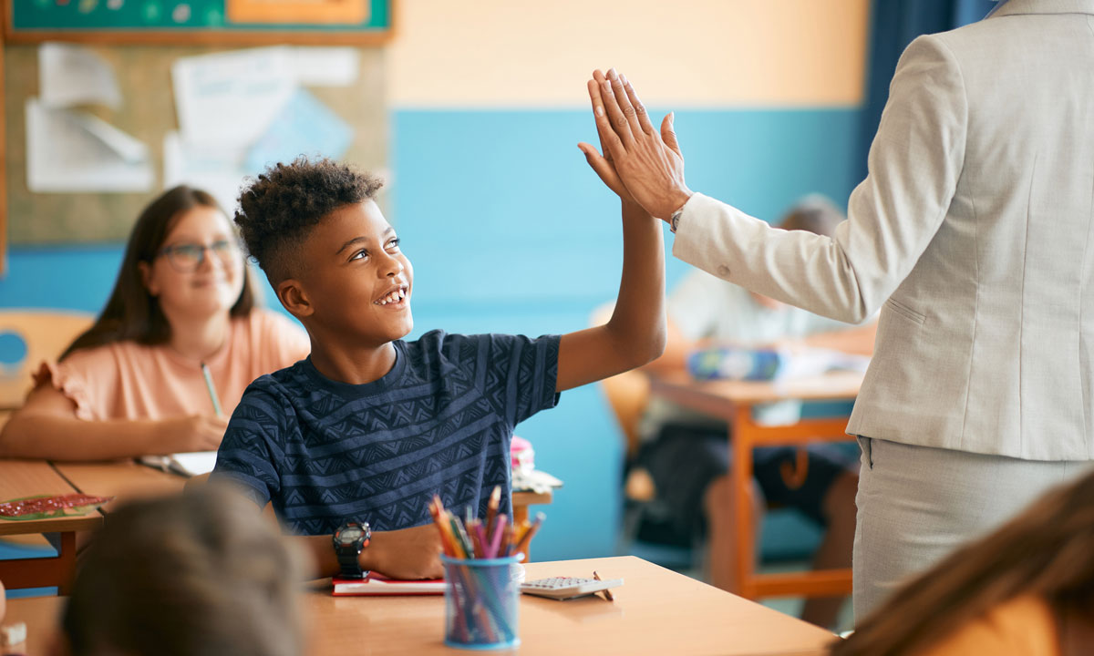 This is a photo of a student and teacher high fiving.